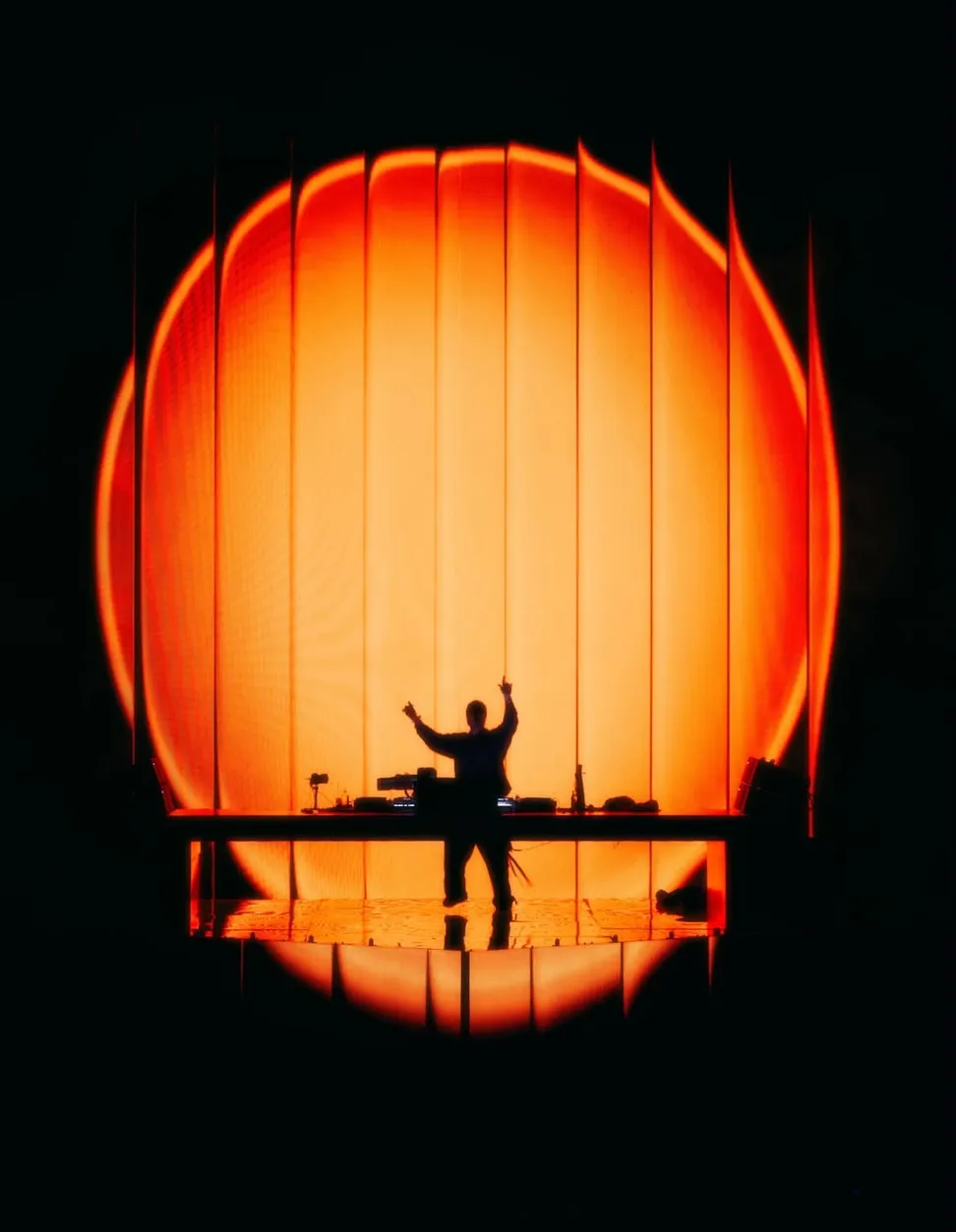 Dimora the warehouse: a DJ silhouetted against an orange light